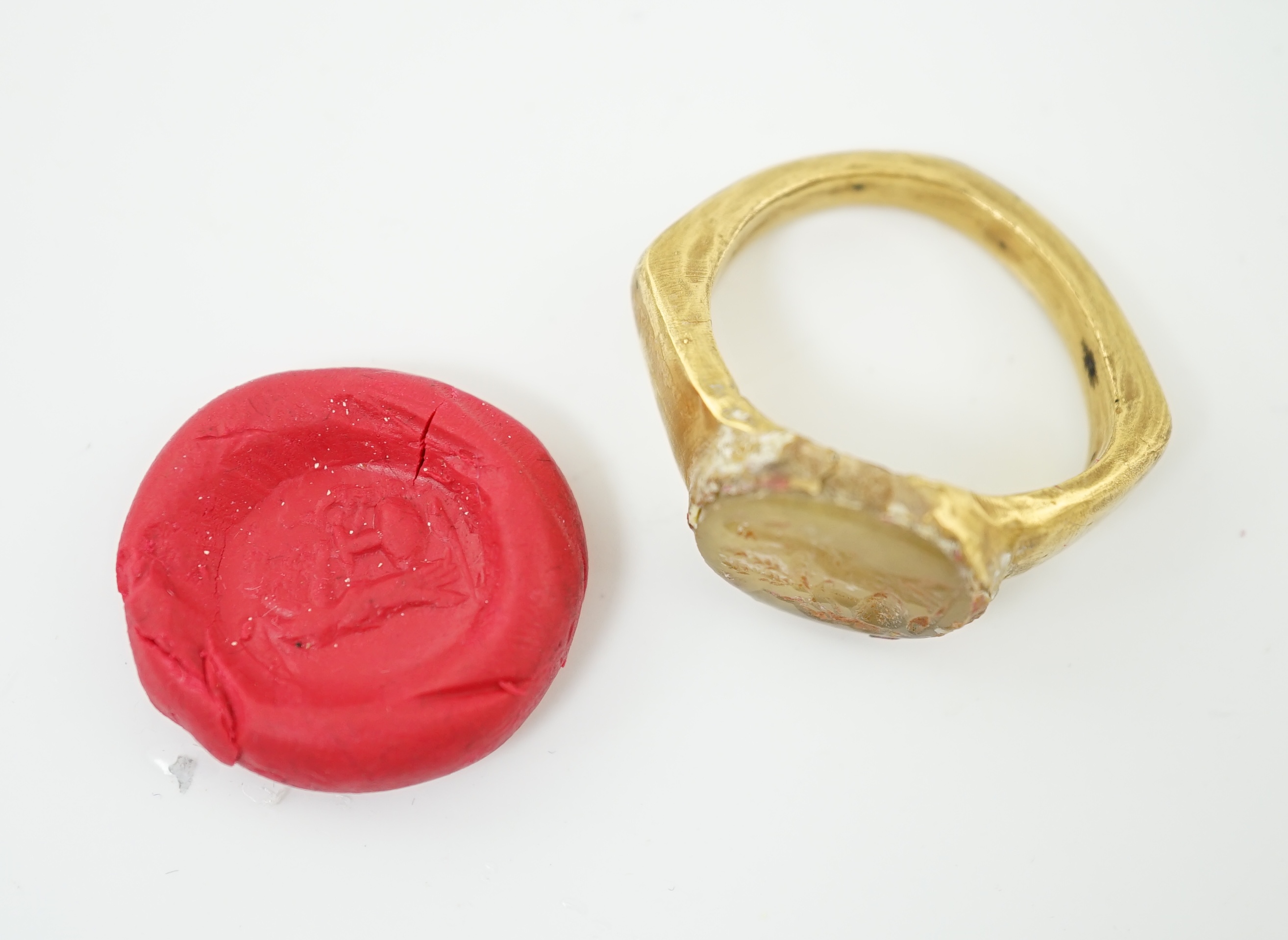 A Roman gold and hardstone intaglio military finger ring, carved with Saturn beside a pedestal